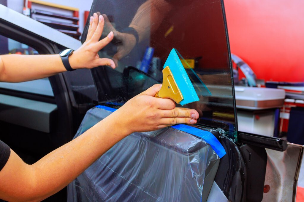 Car window tinting process being performed in an auto shop with focus on meticulous application
